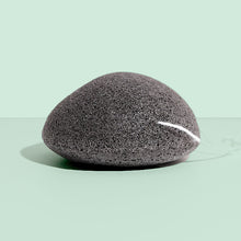 Black natural konjac sponge on a light green background